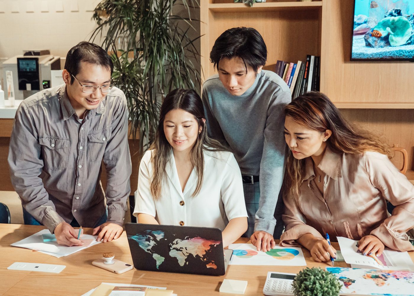 A leadership team in a weekly meeting around one laptop